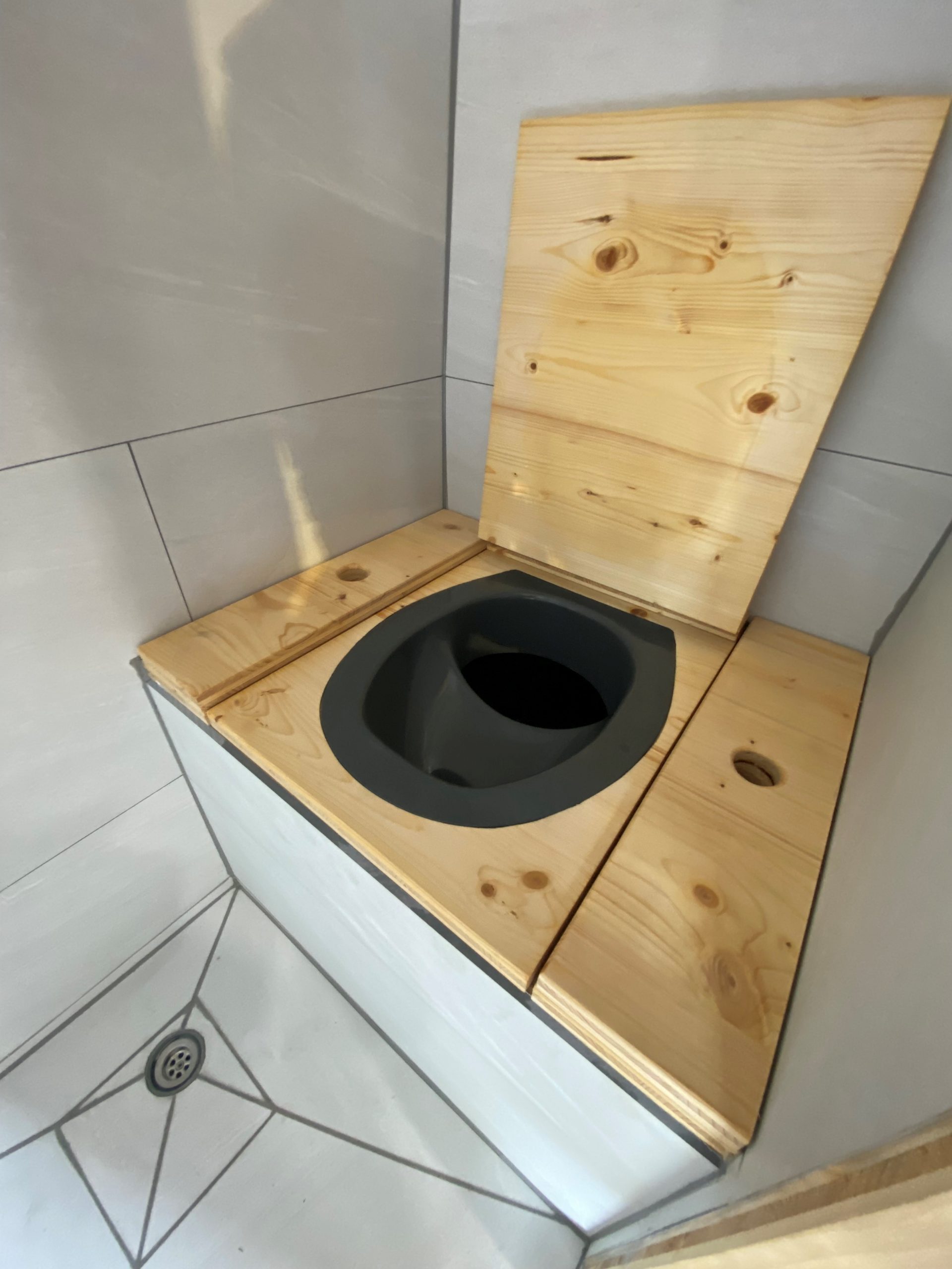 Aménagement de van en Bretagne par un expert. Intérieur élégant avec meubles en bois sur mesure, kitchenette équipée, et salon convertible en lit confortable. Ce van aménagé offre un espace optimisé et fonctionnel, idéal pour les road trips à travers la Bretagne. Exemple parfait de l'aménagement de van haut de gamme.