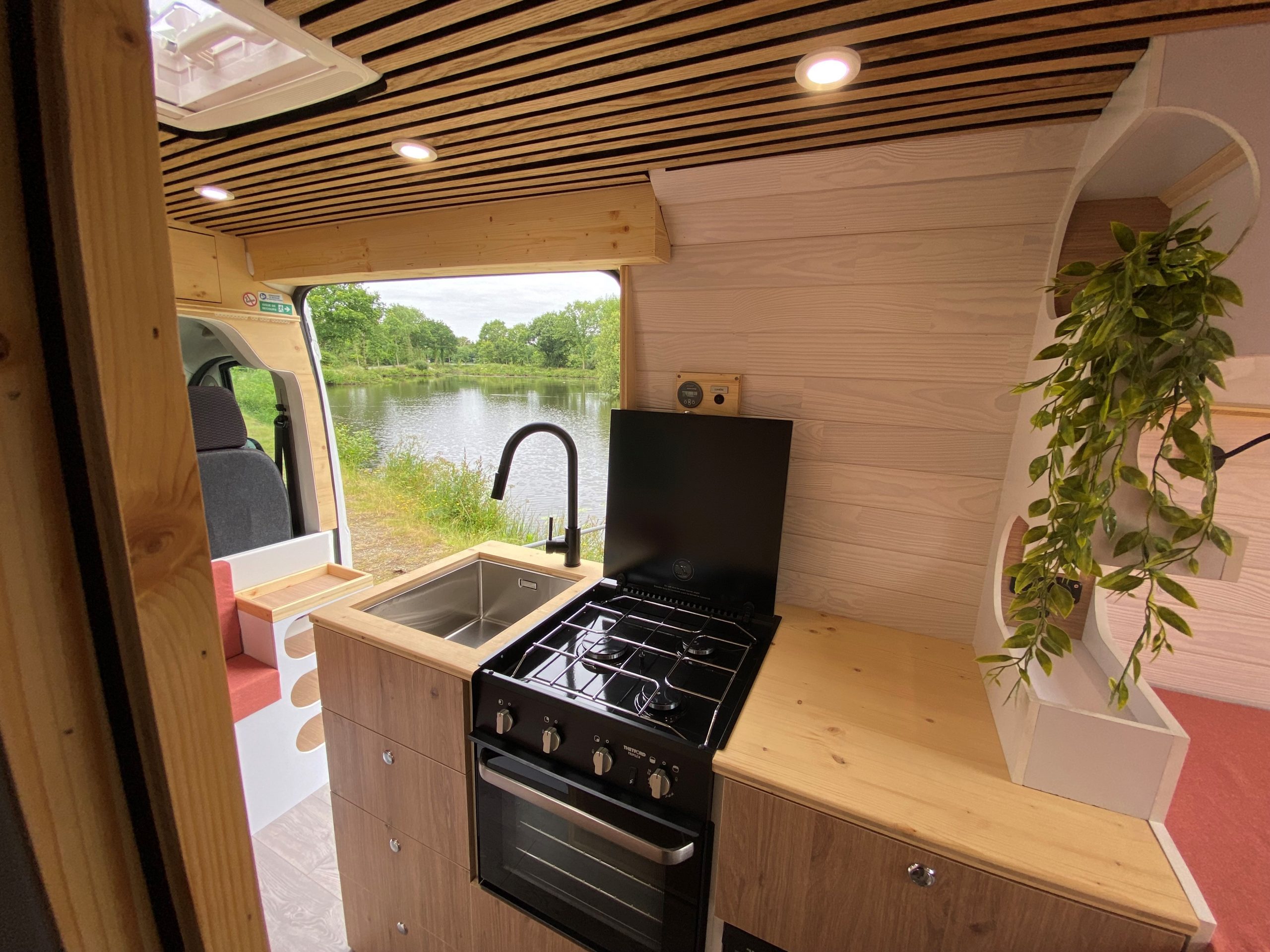 Aménagement sur mesure d'un van en Bretagne, combinant confort et fonctionnalité. Meubles en bois, kitchenette équipée, et salon convertible en lit. Parfait pour explorer la Bretagne en toute liberté. Spécialiste de l'aménagement de van, offrant des solutions personnalisées pour vos voyages.